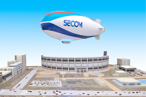 「セコム飛行船」（1/50の都市ジオラマの上に浮く1/3スケールの「セコム飛行船」） 